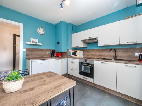 une cuisine avec des armoires blanches et une table en bois dans l'établissement Apartment Les cyclades by Interhome, à Antibes