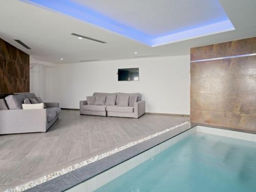 a swimming pool in a living room with two couches at Villa Villa Eos by Interhome in Jávea