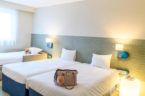 a hotel room with two beds with a bag on the bed at ibis Styles Tours Centre in Tours