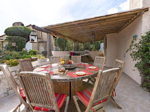 Una mesa y sillas de madera en un patio. en Holiday Home Casa Paulka by Interhome, en Sainte-Lucie de Porto-Vecchio