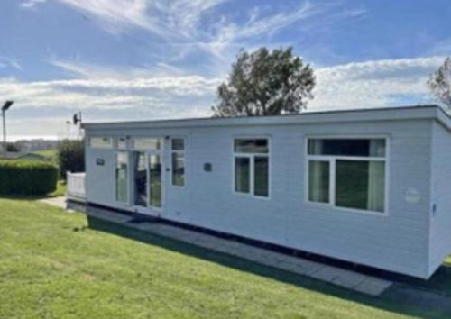 a small white house on a grass field at Inviting 2-Bed Caravan on Combe Haven Holiday Park in Hollington