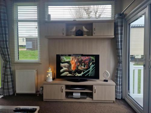 a living room with a flat screen tv on a entertainment center at Inviting 2-Bed Caravan on Combe Haven Holiday Park in Hollington