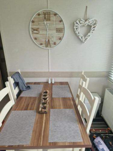 a dining room table with chairs and a clock on the wall at Inviting 2-Bed Caravan on Combe Haven Holiday Park in Hollington