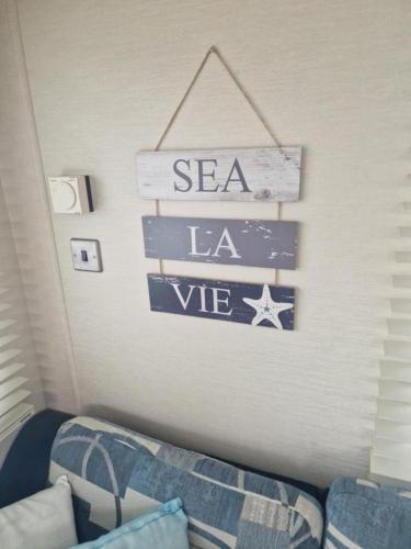 a room with a couch and a sign that says sea la we at Inviting 2-Bed Caravan on Combe Haven Holiday Park in Hollington