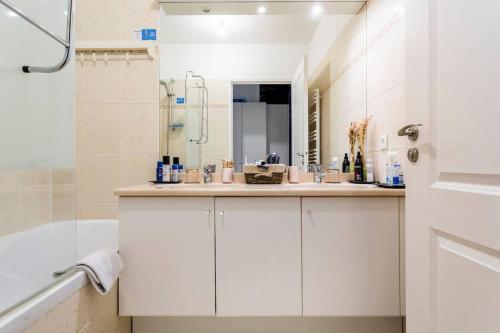 une salle de bain blanche avec une baignoire et un lavabo dans l'établissement Bel appartement spacieux / Proche Arena Paris Sud, à Issy-les-Moulineaux