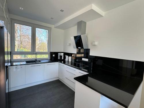 a kitchen with white cabinets and a black counter top at Luxuriöses Ferienhaus nähe Kattowitz in Bytom