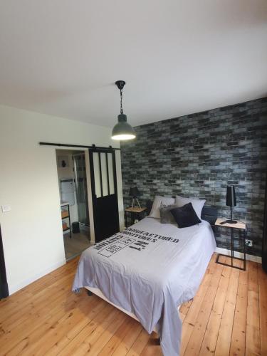 um quarto com uma cama e uma parede de tijolos em chez Marie et Patrick em Chaulnes