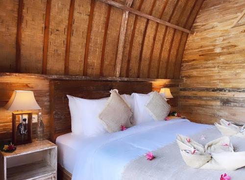 - une chambre avec un grand lit blanc et des murs en bois dans l'établissement Penida Green Palm Cottage, à Toyapakeh
