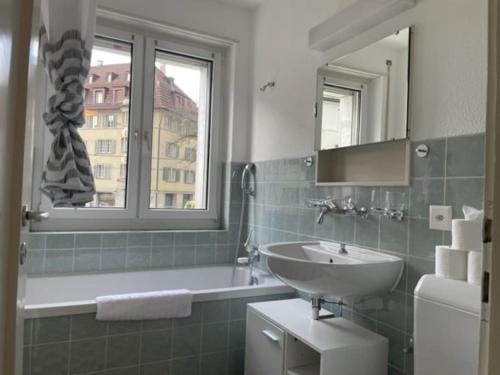 a bathroom with a sink and a mirror and a tub at Cozy, sunny, city center 1 bedroom flat (Marble 3) in Zurich