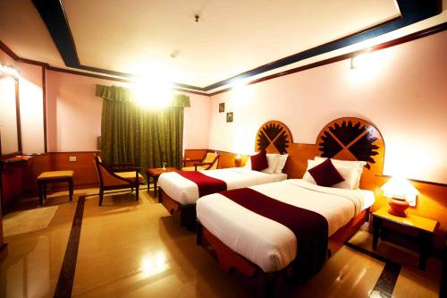 a hotel room with two beds and a table and chairs at The Surya, Cochin in Angamali