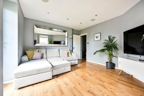 a living room with a white couch and a flat screen tv at Cosy 1-Bed E15, sleeps 4, 1 min from tube Station Near O2 Arena in London