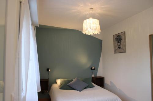 a bedroom with a bed and a chandelier at Le Petit Saule - Gîte entre Beauval et Chenonceau in Faverolles-sur-Cher