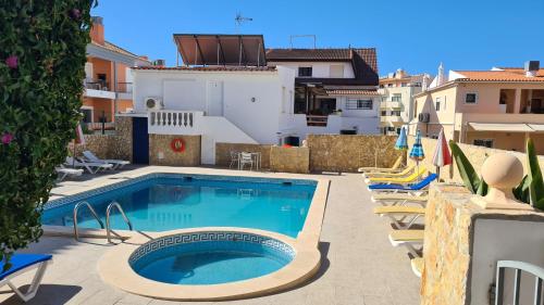 a swimming pool with lounge chairs next to a building at APARTAMENTOS CABRITA in Olhos de Água