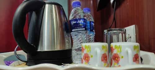 Fālākāta的住宿－HOTEL NANDANIK PALACE，茶壶和桌子上的杯子及一瓶水