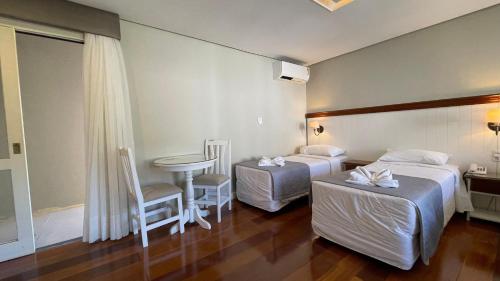 a hotel room with two beds and a table at Pousada Golden Hills in Canela