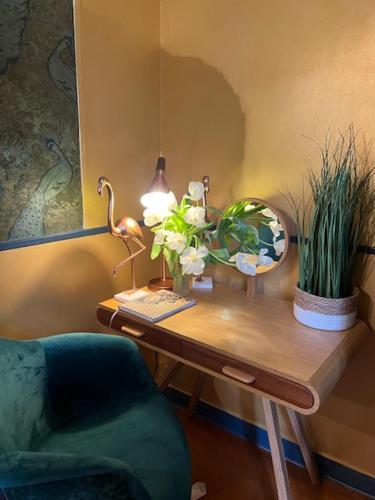 a desk with a lamp and a chair and flowers on it at Chambres d'Hôtes & SPA Le Chat Chez Qui j'Habite in Saint-Aubin-sur-Mer
