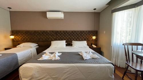 two beds in a hotel room with towels on the bed at Pousada Golden Hills in Canela