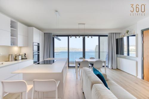 Il dispose d'une cuisine et d'un salon avec une grande table et des chaises blanches. dans l'établissement Designer 2BR home with Stunning views in St Pauls by 360 Estates, à San Pawl il-Baħar