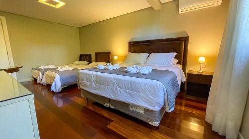a bedroom with two beds with white sheets at Pousada Golden Hills in Canela