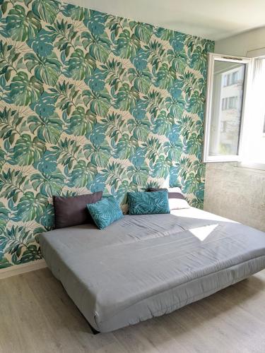 a bed in a room with a wall covered in wallpaper at Joli studio lumineux avec parking, proche gare in Chelles