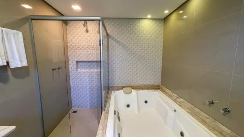 a bathroom with a tub and a glass shower at Pousada Golden Hills in Canela