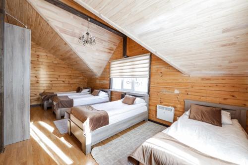 three beds in a room with wooden walls at Ski Paradise Karakol in Karakol