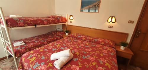 una camera d'albergo con due letti e lenzuola rosse di Hotel Alessi** Rimini a Rimini