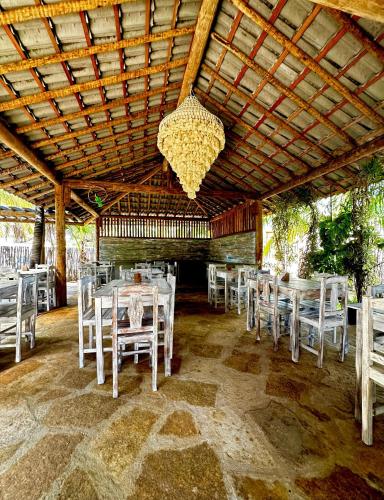 a dining room with white tables and chairs and a chandelier at Pousada Vento do Kite in Barra Grande