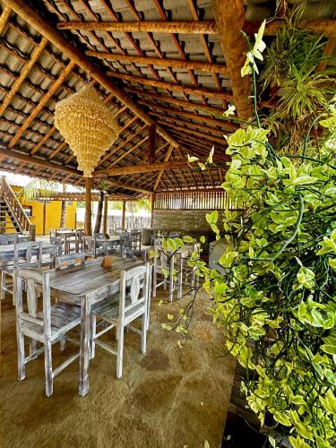 a table and chairs under a wooden roof at Pousada Vento do Kite in Barra Grande