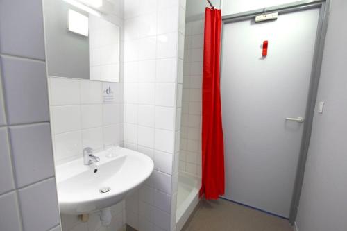 a bathroom with a sink and a red shower curtain at Auberge La Digue in Calais