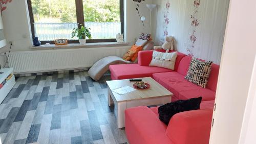 a living room with a red couch and a table at Ferienhaus Kunterbunt in Hitzacker