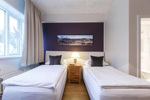 two twin beds in a room with a window at Centrum Hotel in Akureyri