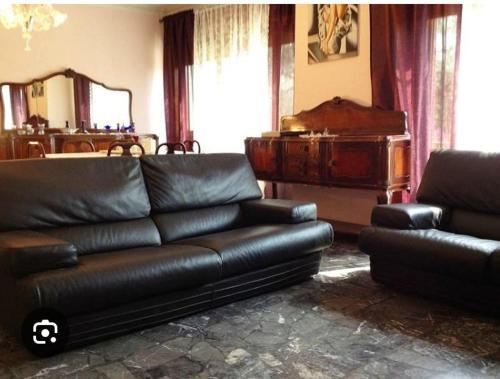 a living room with a leather couch and a piano at Villa in campagna in Calvisano