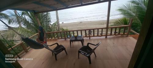 a hammock on a balcony with a view of the beach at CABAÑA TELLO SURF in Nuquí