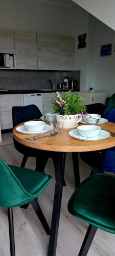 a wooden table with plates and flowers on top of it at Apartament Pogodny in Łeba