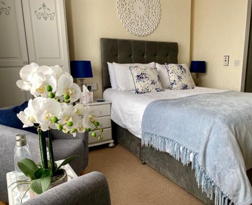 1 dormitorio con 1 cama y un jarrón de flores en The Wadham, en Weymouth