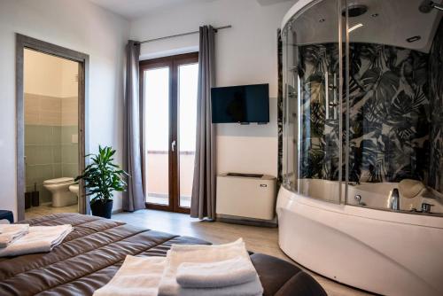 um quarto com uma banheira, uma cama e uma televisão em Albamarina em SantʼAntìoco