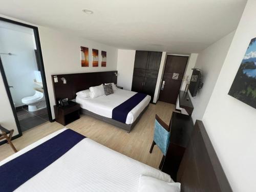 a hotel room with two beds and a bathroom at Hotel H53 in Sogamoso