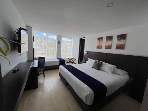 ein Hotelzimmer mit 2 Betten und einem Schreibtisch in der Unterkunft Hotel H53 in Sogamoso