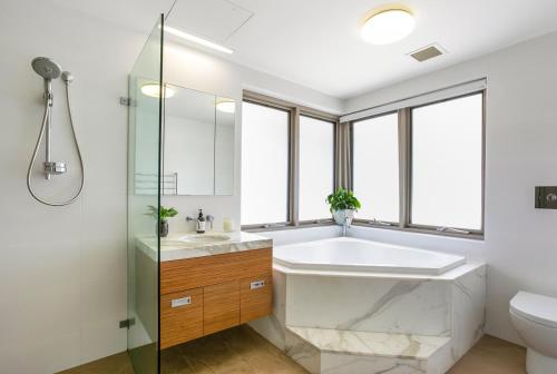 a bathroom with a tub and a sink and a toilet at Manly Harbourside Villa in Sydney