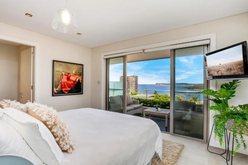 a bedroom with a large white bed and a large window at Manly Harbourside Villa in Sydney