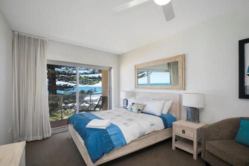 a bedroom with a bed and a couch and a window at Beachfront Dream - Direct Beachfront in Narrabeen
