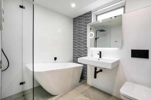bagno bianco con lavandino e specchio di Yulunga - Direct Beachfront a Narrabeen