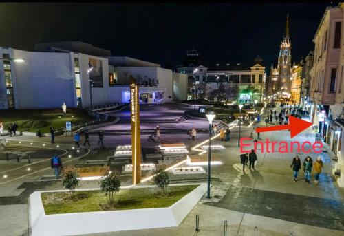 Blick auf eine Stadt in der Nacht mit einem orangenen Pfeil in der Unterkunft Theatre Square Apartments in Novi Sad