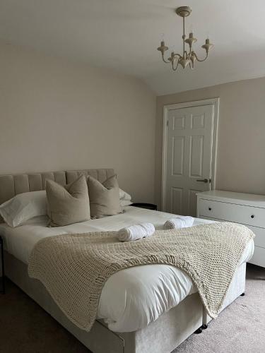 a white bedroom with a large bed with a chandelier at Rickmansworth Lodge in Watford