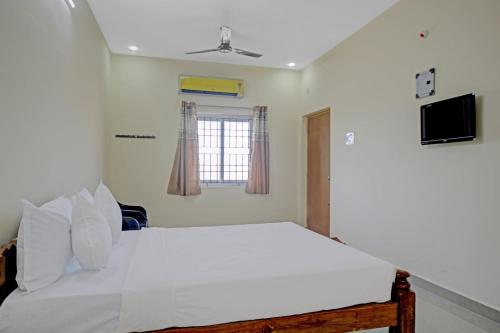 a bedroom with a white bed and a window at Super Hotel O Vsv Guest House in Chennai