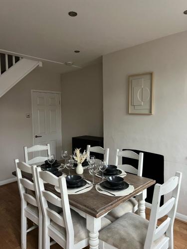 Rickmansworth Lodge في واتفورد: طاولة طعام مع كراسي بيضاء وطاولة طعام