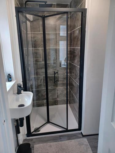 um chuveiro com uma porta de vidro ao lado de um lavatório em Eskdale Durham DH1 em Durham
