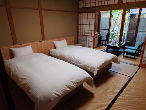 two beds in a room with a table and a chair at Ryoso Yufuin Yamadaya in Yufuin