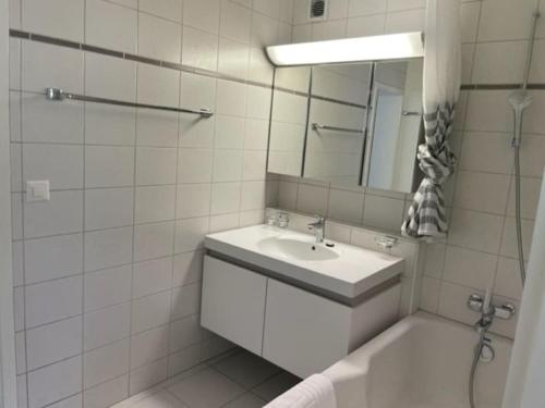 W białej łazience znajduje się umywalka i lustro. w obiekcie Beautiful, quite and very central 2 bedroom flat (Sky6) w Zurychu